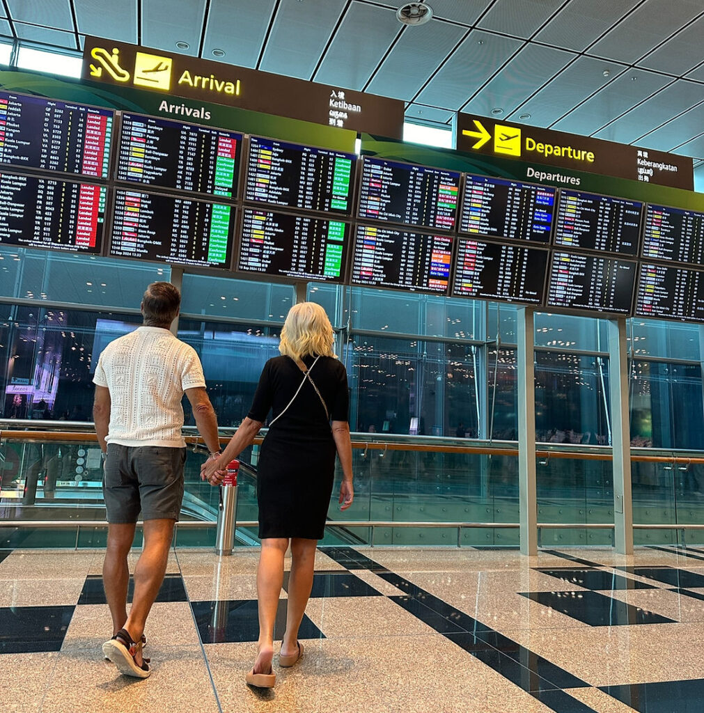 Shayne and Shelly checking the departure board at Singapore airport on their visa run trip.