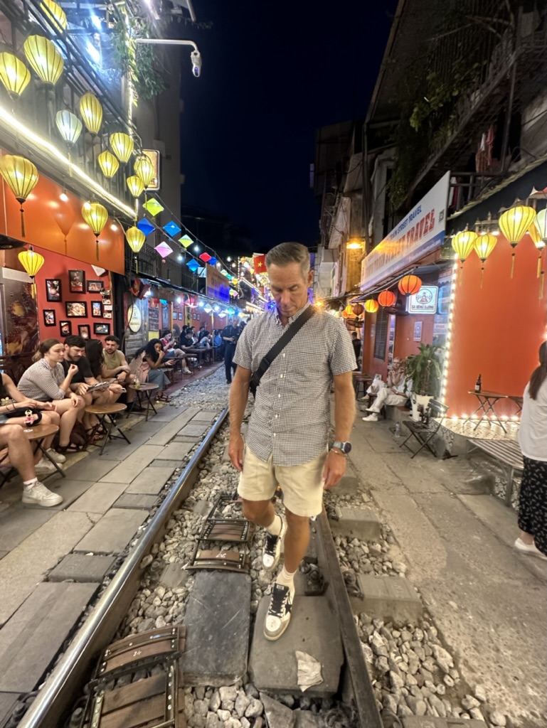 Shayne on the famous train street in Vietnam, one of the places where your travel dollar goes further